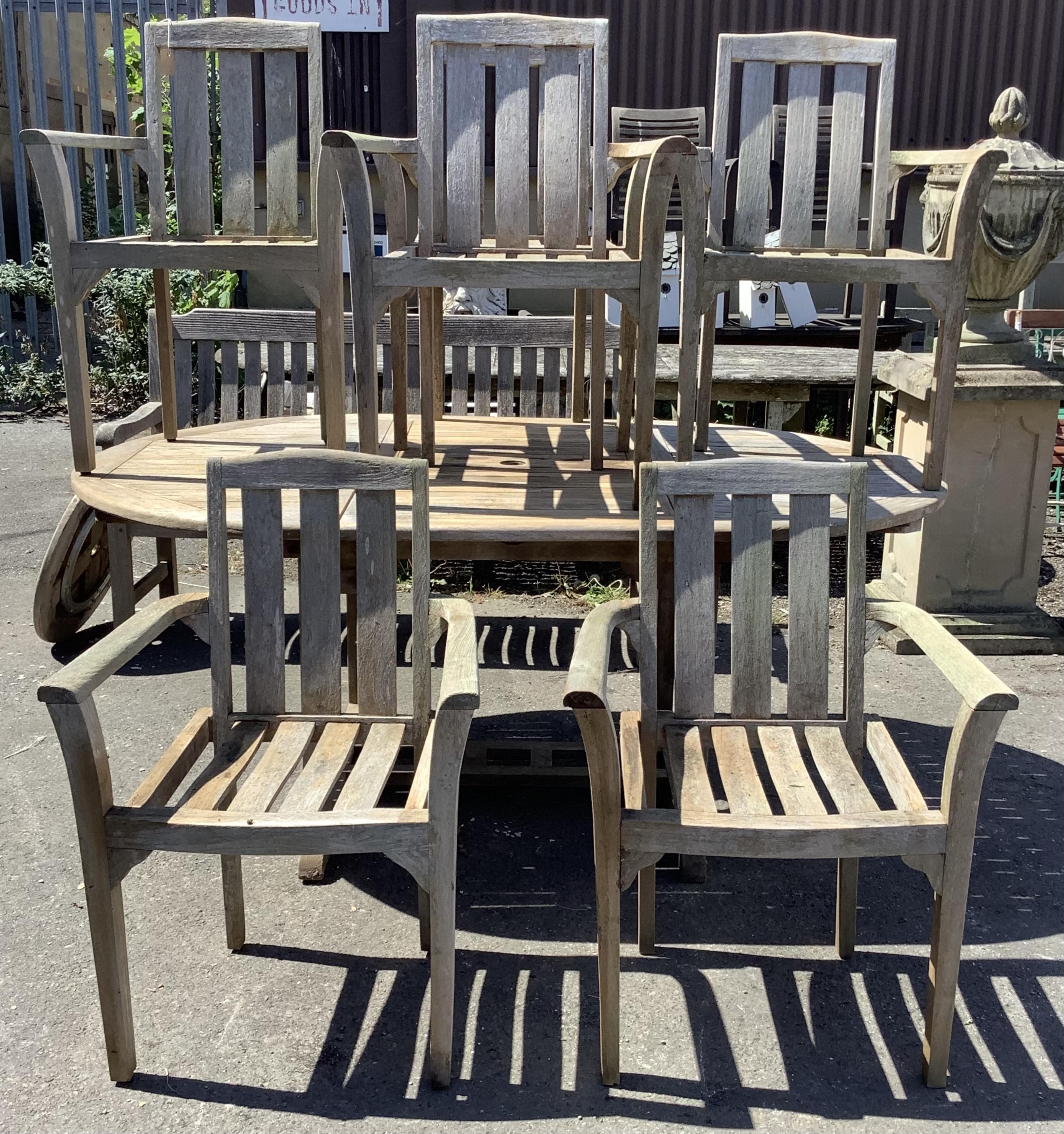 Six Sherwood teak elbow chairs, a weathered teak oval extending garden table, 181cm extended, depth 120cm, height 74cm and a lazy Susan